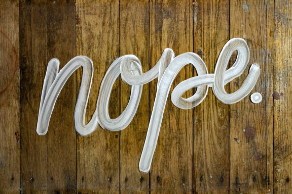 Der Schriftzug "nope." auf einer braunen Holzoberfläche.